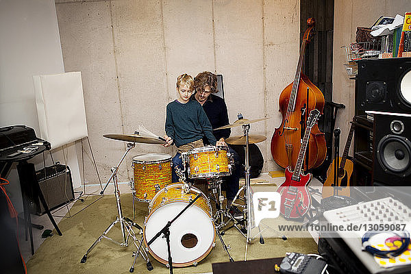 Father teaching son to play drums at home
