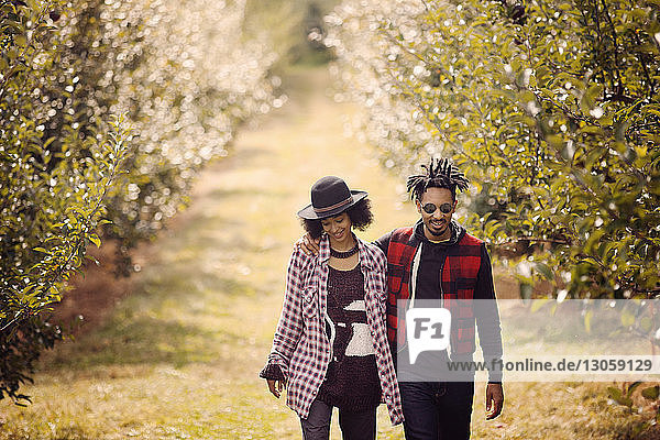 Lächelndes Paar beim Spaziergang im Obstgarten