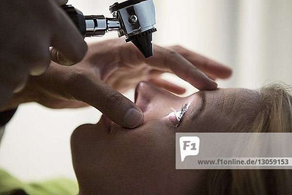 Close-up of doctor examining patient's eye with Otoscope in hospital
