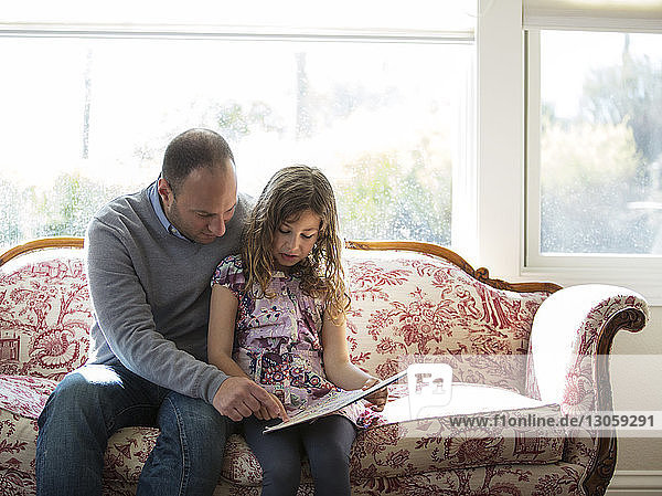 Vater unterrichtet Tochter zu Hause auf dem Sofa