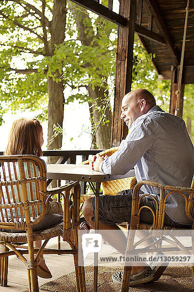 Vater spricht mit Tochter  während er im Pavillon am Tisch sitzt