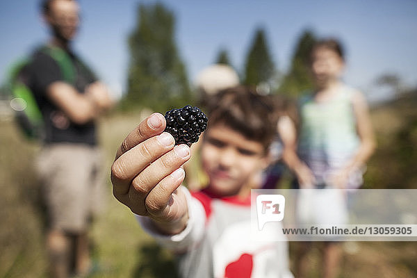 Boy holding blackberry while family standing in background