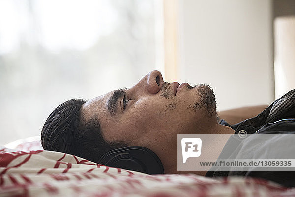 Close-up man with headphone lying on bed