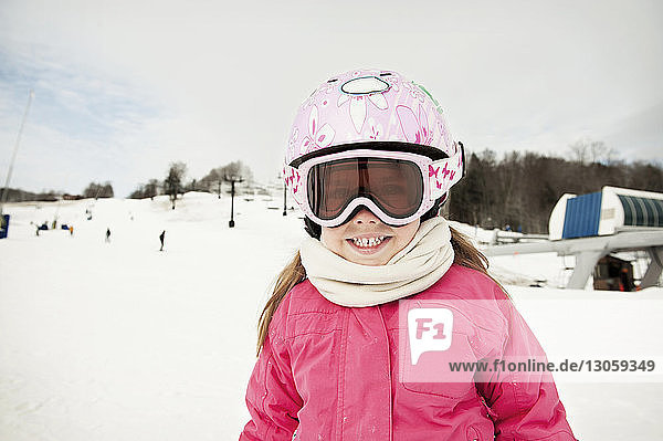 Portrait of happy girl in ski-wear on snow covered mountain