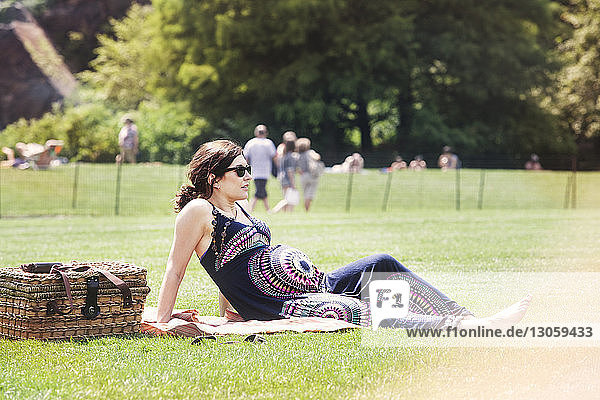 Schwangere Frau sitzt auf Grasfeld im Park
