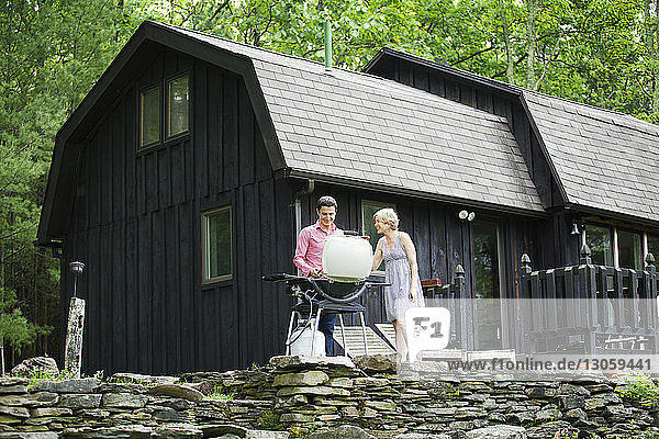 Ehepaar bereitet Essen auf dem Grill vor  während es an der Hütte steht