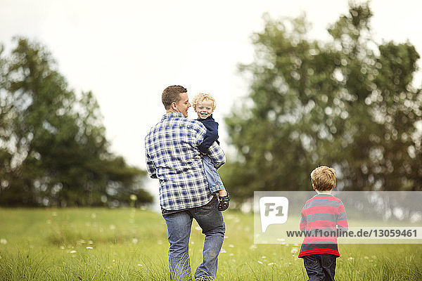 Happy father with sons on grassy field