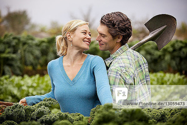 Romantischer Mann hält Schaufel  während er bei der Frau auf dem Bauernhof steht