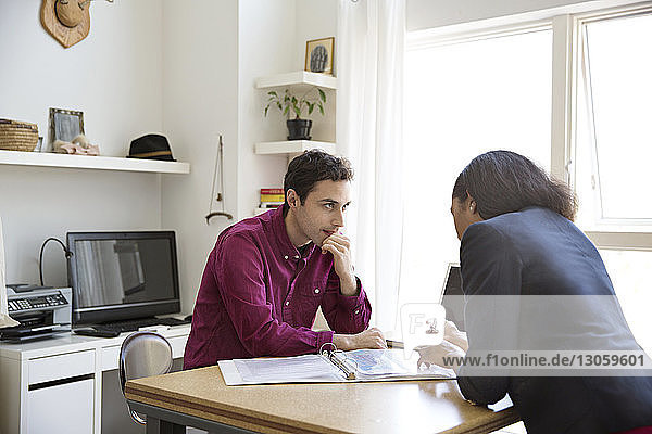 Business people having discussion over documents at desk in creative office