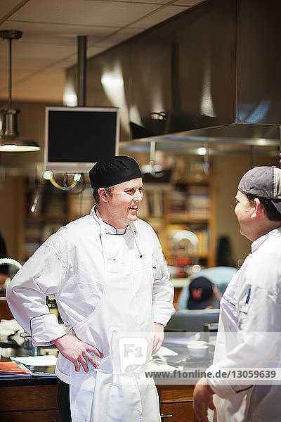 Male chefs talking while standing in commercial kitchen