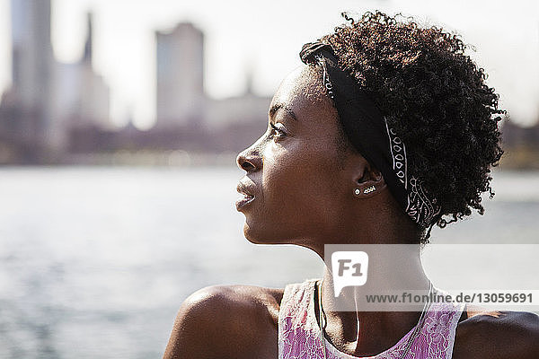 Portrait of thoughtful woman against river in city