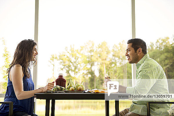 Seitenansicht eines Paares  das während des Essens am Tisch diskutiert