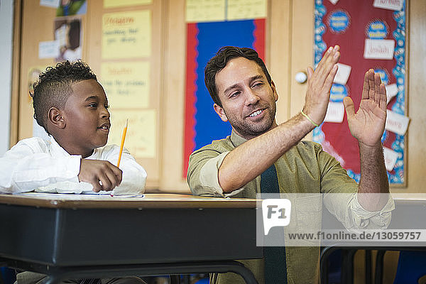 Glückliche Lehrerin erklärt dem Jungen im Klassenzimmer