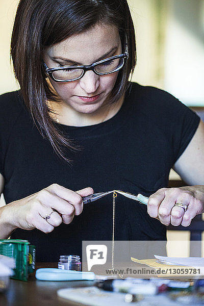 Close-up of female artist making jewelry at table in workshop