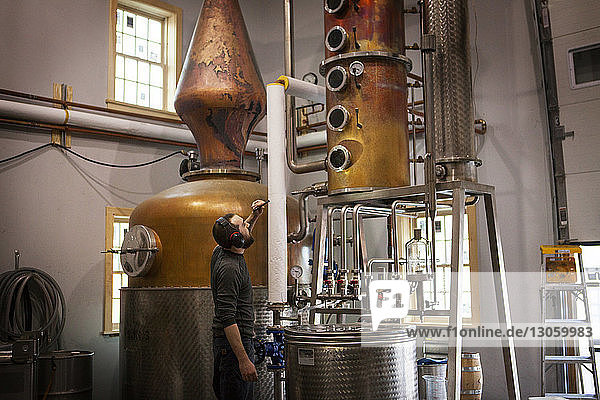 Side view of man looking at machinery at distillery