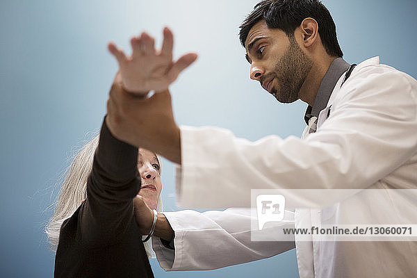 Doctor examining patient against wall in hospital