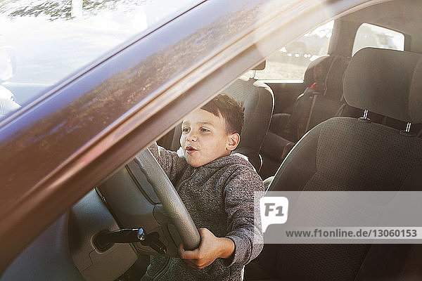 Boy pretending to drive while sitting in car