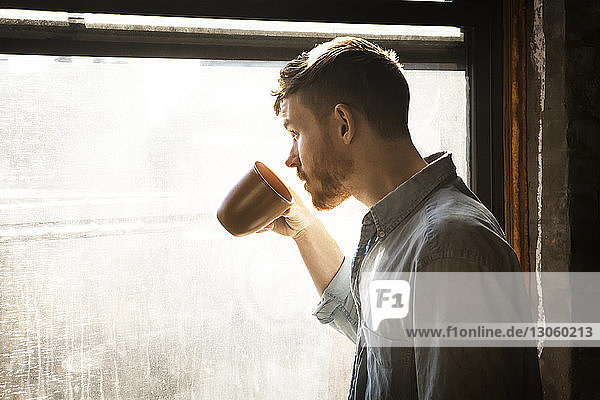 Man looking away while drinking coffee