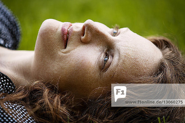 Close-up of thoughtful woman lying on field