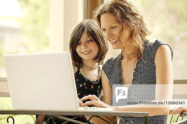 Mother and daughter using laptop computer while sitting at home