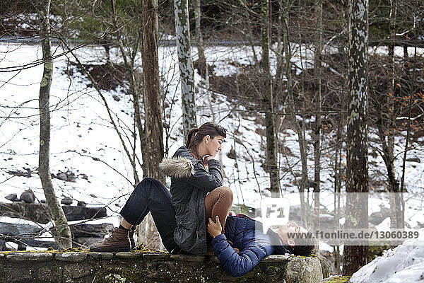 Couple on retaining wall in forest