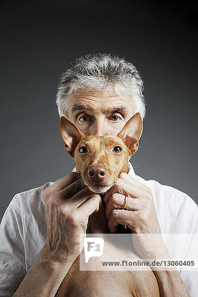 Portrait of man and dog against gray background