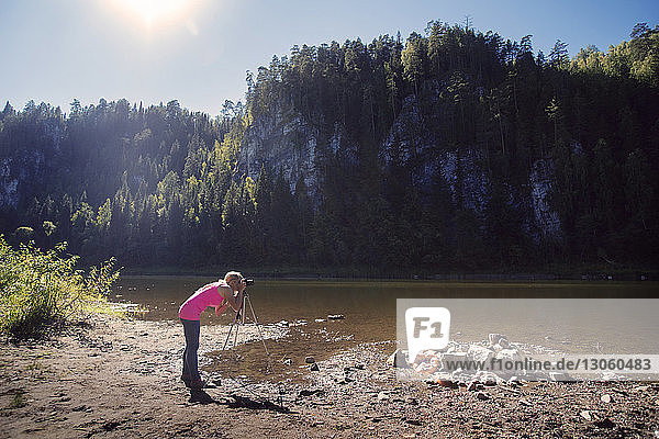 Woman photographing with camera on riverbank