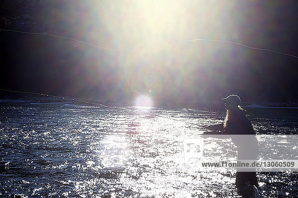 Seitenansicht einer Frau  die an einem sonnigen Tag im See fischt