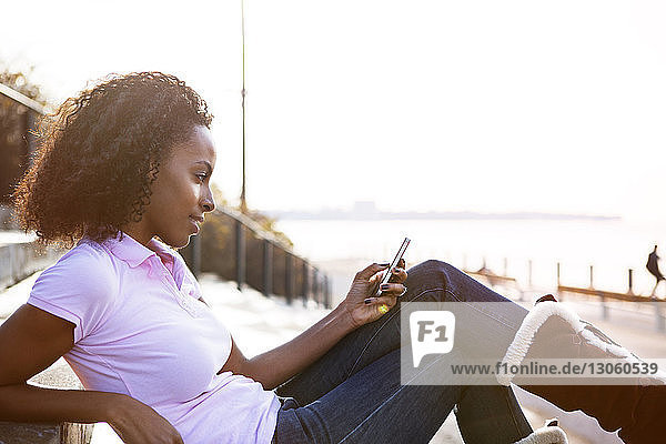 Young woman using phone while sitting on steps