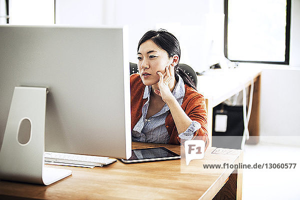 Geschäftsfrau  die am Computer arbeitet  während sie im Büro am Tisch sitzt