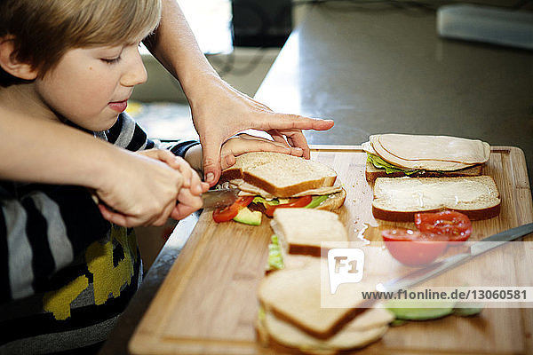 Beschnittenes Bild eines Vaters  der mit seinem Sohn in der Küche ein Sandwich macht