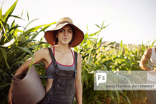 Portrait of woman carrying basket while standing in farm