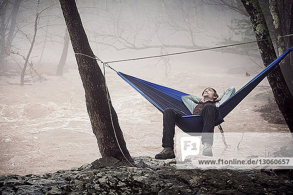 Mann entspannt sich auf Hängematte im Wald