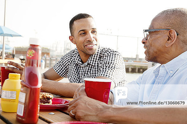 Glücklicher Sohn und Vater bei Getränken und Snacks am Tisch in der Stadt
