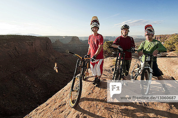 Portrait of mountain bikers with bicycles standing on cliff