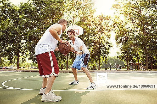 Freunde spielen Basketball auf dem Platz im Park