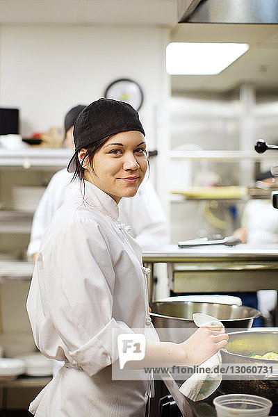Portrait of happy female chef preparing food in commercial kitchen
