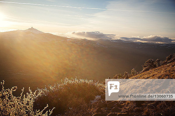 Fernsicht einer Frau  die am sonnigen Tag auf einem Hügel vor den Bergen steht