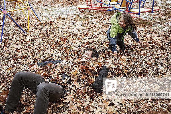 Boy throwing leaves on father while playing in park