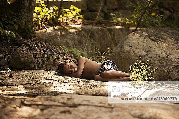 Junge schläft auf Felsen im Wald