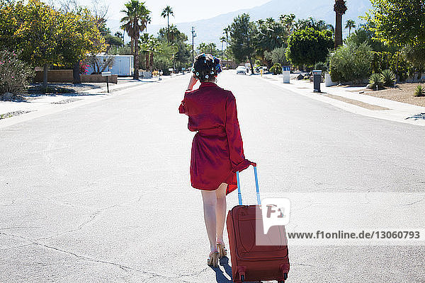 Rear view of woman with suitcase walking on street