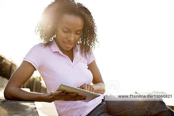 Junge Frau mit Tablet-Computer auf der Treppe an einem sonnigen Tag
