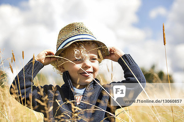 Close-up of happy boy wearing hat standing amidst plants