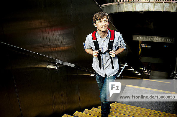 Mann schaut weg  während er in der U-Bahn auf einer Treppe geht