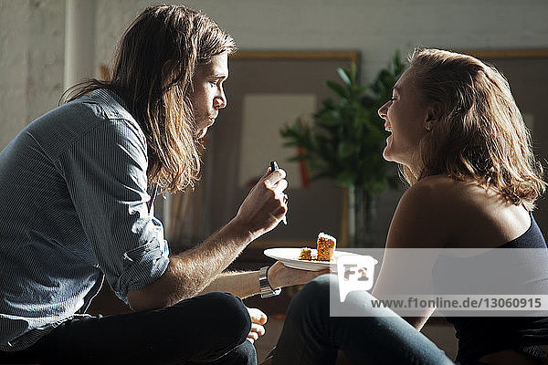Side view of couple eating together while sitting at home
