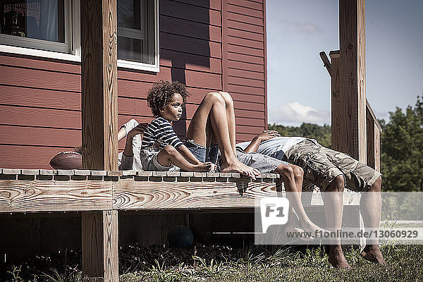 Junge schaut weg  während er mit seiner Familie auf der Veranda sitzt