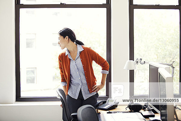 Businesswoman looking through window while standing in office