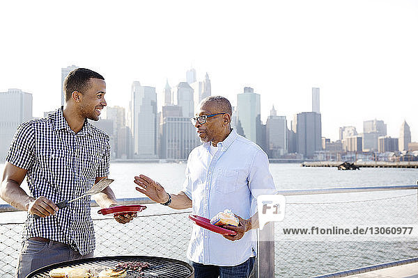 Glücklicher Sohn und Vater unterhalten sich beim Zubereiten von Essen am East River in der Stadt