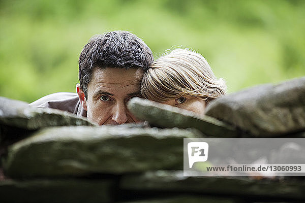 Couple hiding behind stone wall
