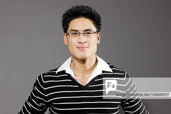 Portrait of confident man standing against grey background